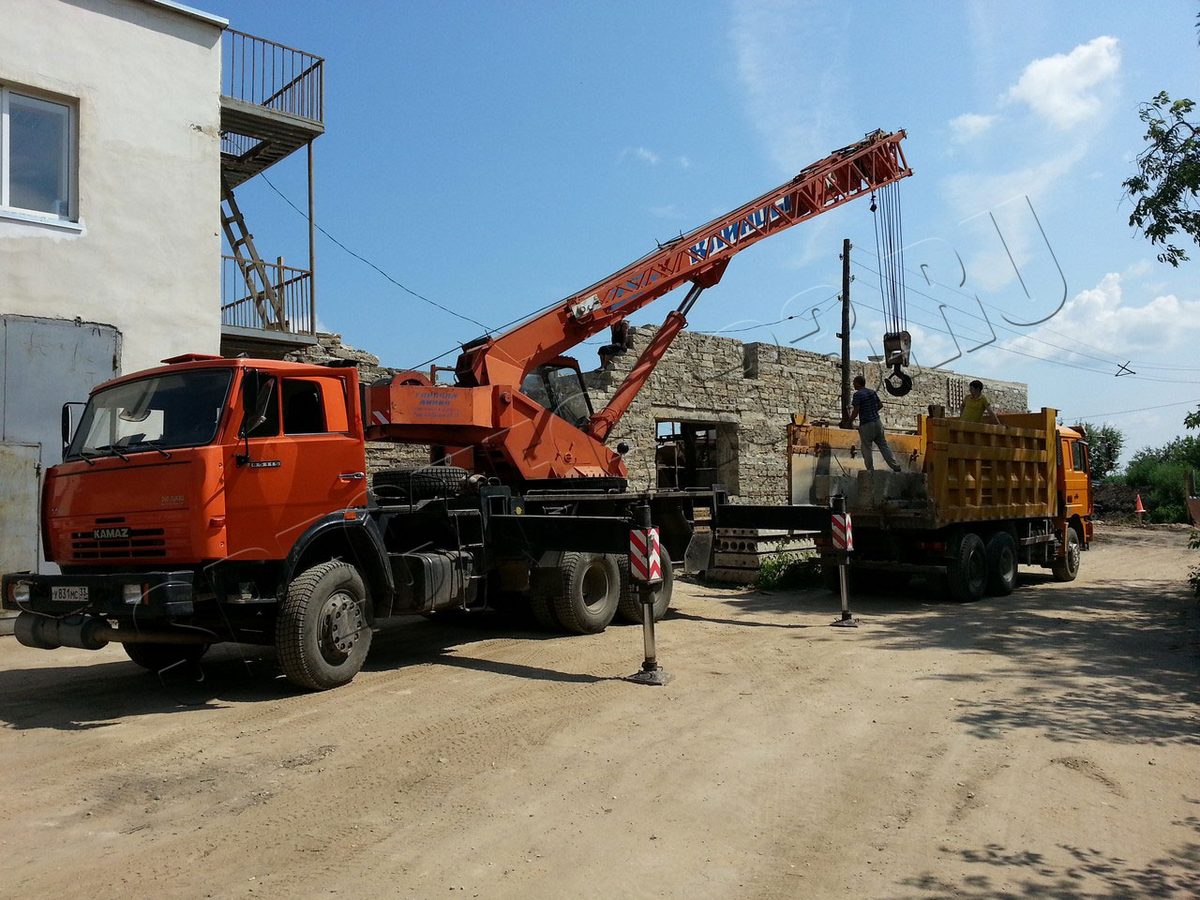 Автокран поднимает конструкцию на объекте